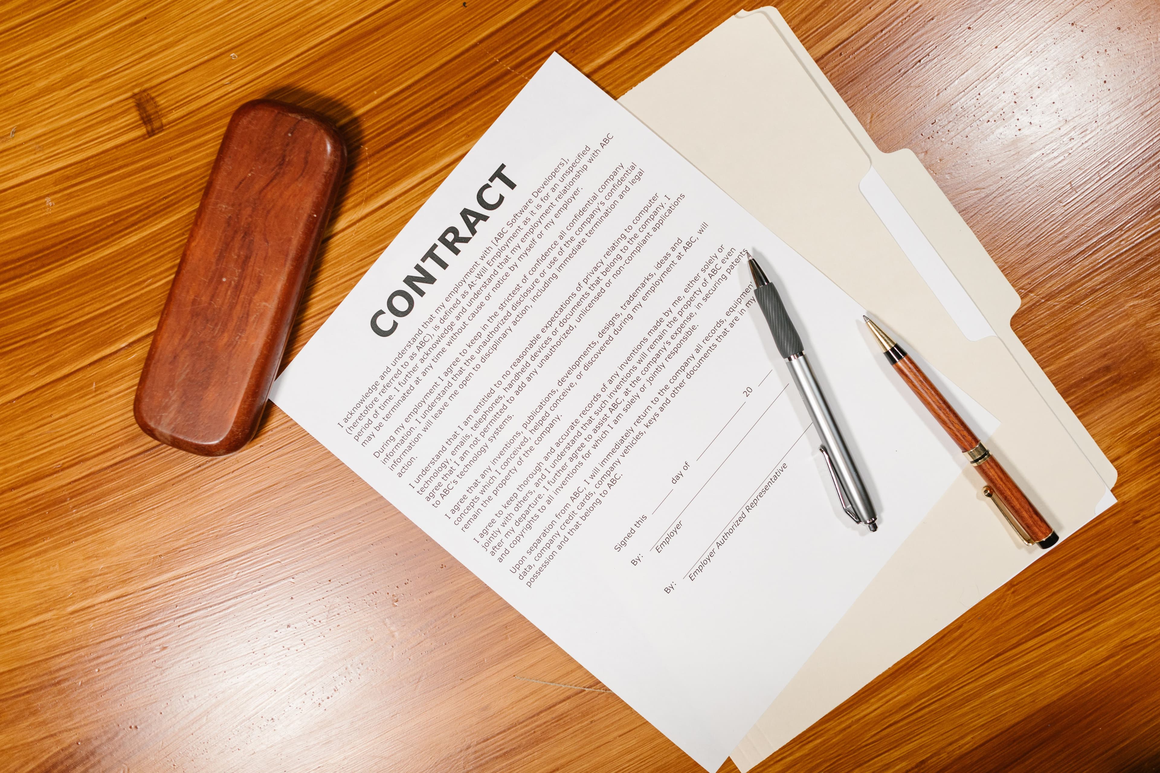 A contract document with pens on a wooden desk
